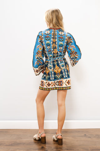 Person wearing a blue embroidered dress with a white background