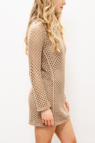 Woman wearing a beige knitted dress against a white background