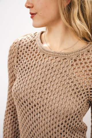 Close-up of a person wearing a beige crochet sweater against a white background