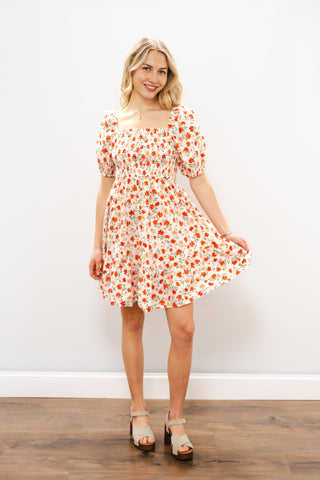 Woman wearing a floral dress against a white wall