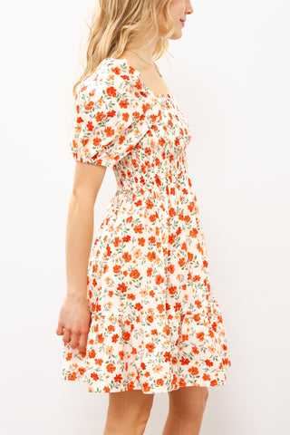 Woman wearing a floral dress with orange flowers on a white background