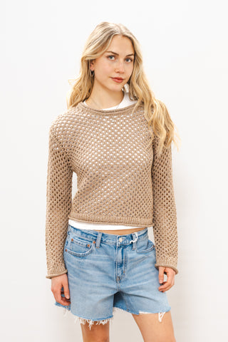 Woman wearing a beige knitted sweater and denim shorts on a white background