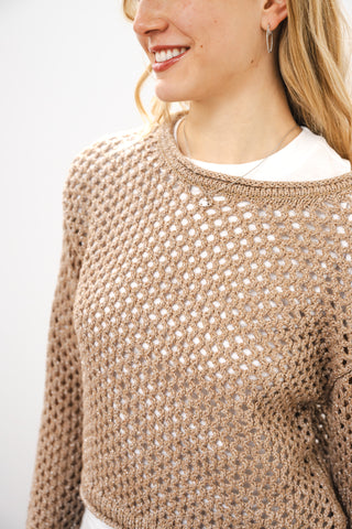 Person wearing a brown knitted sweater with a plain background