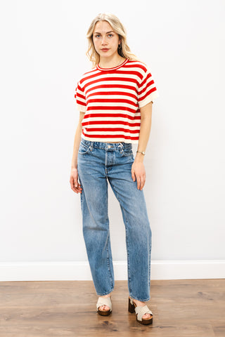 Woman wearing a red and white striped shirt and blue jeans against a white background