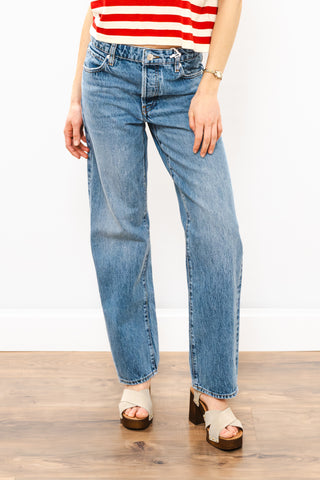 Person wearing blue jeans and a red and white striped shirt on a wooden floor.