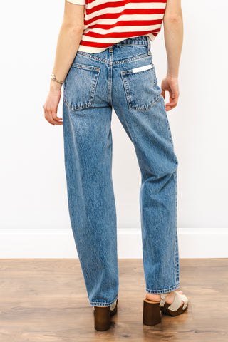 Person wearing blue jeans and a red and white striped shirt on a wooden floor.