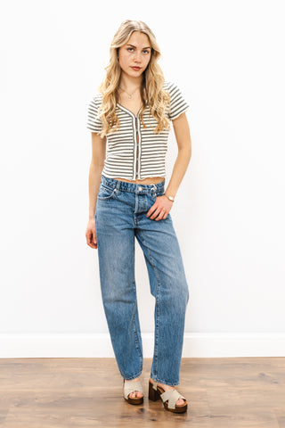 Woman wearing a striped shirt and blue jeans against a white background