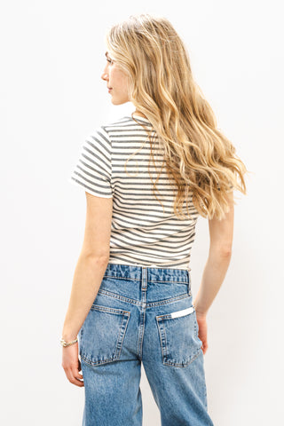 Woman wearing a striped shirt and blue jeans against a white background