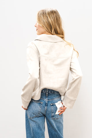 Person wearing a beige jacket and blue jeans on a white background