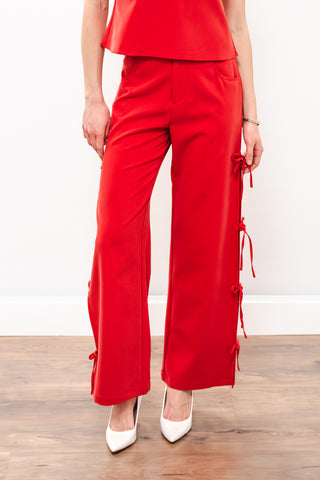 red pants with bows on the side and white heels