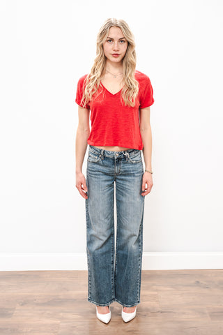 Woman wearing a red top and blue jeans on a white background