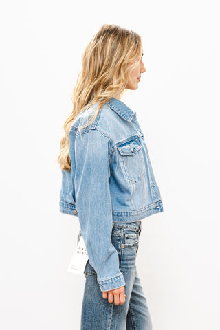 Woman wearing a light blue denim jacket on a white background