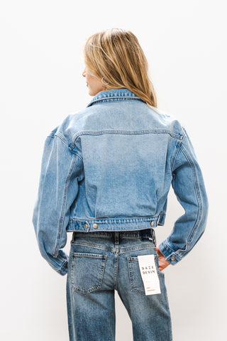 Person wearing a blue denim jacket and jeans on a white background