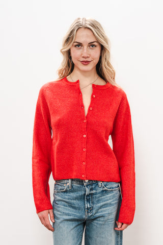 Woman wearing a red cardigan and blue jeans against a white background