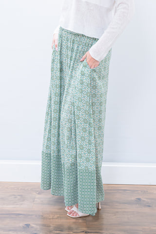 Person wearing a green patterned skirt with a white background