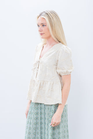 Woman wearing a light-colored blouse and patterned skirt on a white background