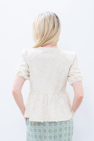 Person wearing a light-colored cardigan over a patterned skirt on a white background