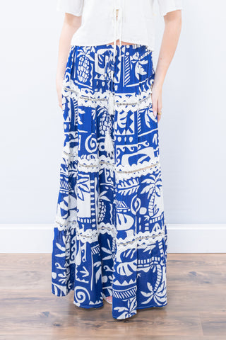 Person wearing a blue and white patterned skirt with lace details on a plain background