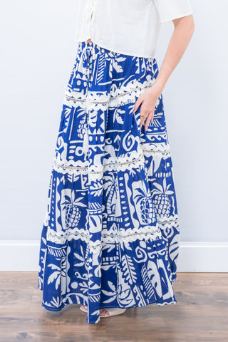 Blue and white patterned skirt worn by a person on a wooden floor.