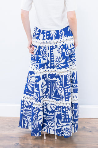 Person wearing a blue and white patterned skirt with a plain background