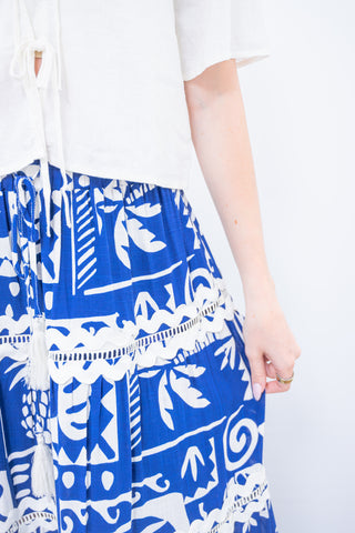 Blue and white patterned skirt worn by a person on a white background