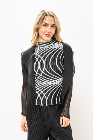 Woman wearing a black and white patterned top with sheer sleeves on a white background