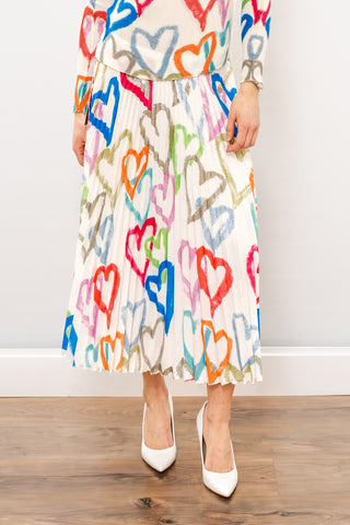 a woman standing against a white background in a colorful skirt
