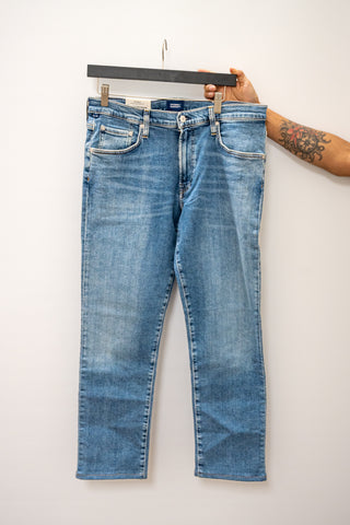 Blue jeans on a hanger against a white background