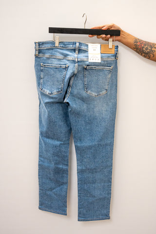 Blue jeans on a hanger against a white background