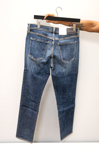 Blue jeans on a hanger against a white background