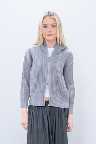Woman wearing a gray ribbed knit cardigan over a white top and gray skirt on a light blue background