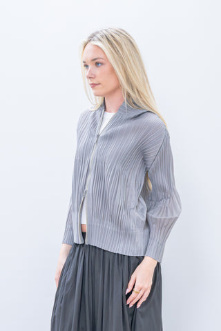 Woman wearing a gray pleated outfit against a white background
