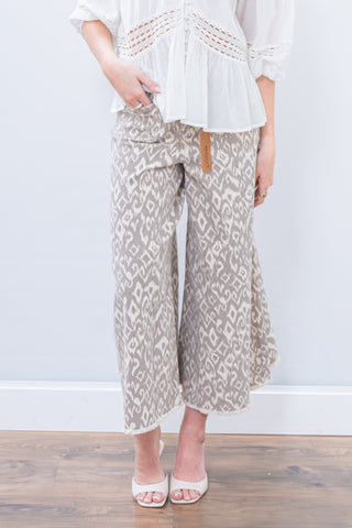 Person wearing a white top and patterned pants on a plain background