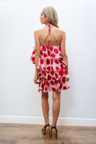 Woman wearing a red floral dress with a white wall background