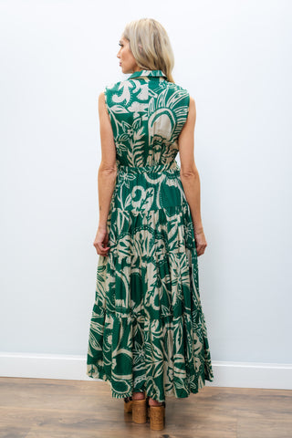 Woman wearing a green floral dress against a white wall.
